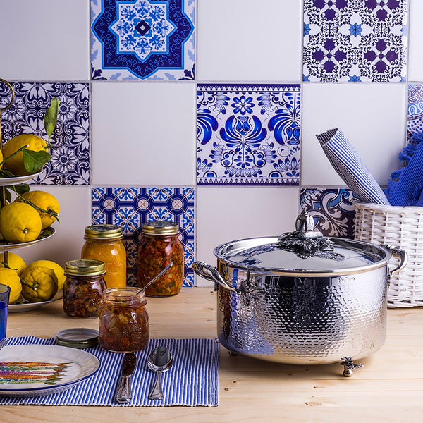 Stockpot in the kitchen with fresh lemons and relishes in jars.