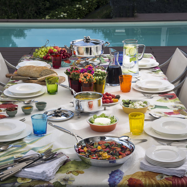 Poolside meal set with hand-hammered clad stainless steel cookware filled with soups, breads, and veggies